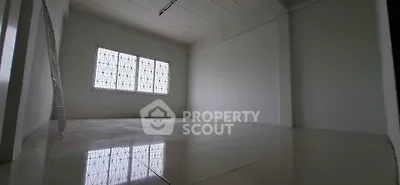 Spacious empty room with tiled flooring and large window, ideal for customization.