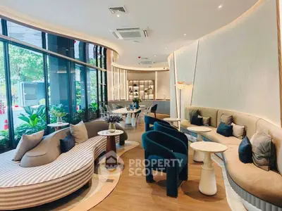 Luxurious modern living room with elegant curved sofas and large windows overlooking greenery.
