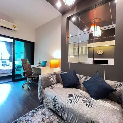Modern living room with stylish decor and open view to bedroom, featuring cozy sofa and workspace.