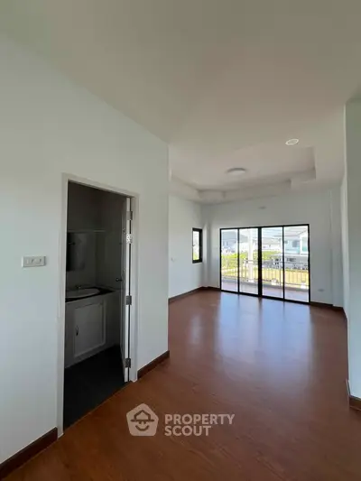 Spacious living room with large windows and wooden flooring, offering ample natural light and a modern design.