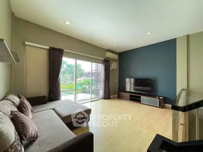 Spacious living room with modern decor and large windows opening to a balcony with a view.