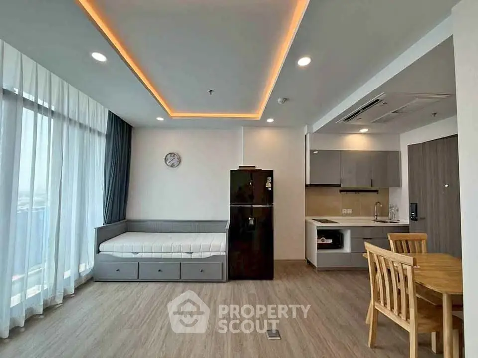 Modern open-layout living room with kitchen, featuring sleek furniture and ambient lighting.