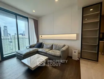 Modern living room with city view, featuring a sleek gray sofa and marble coffee table.