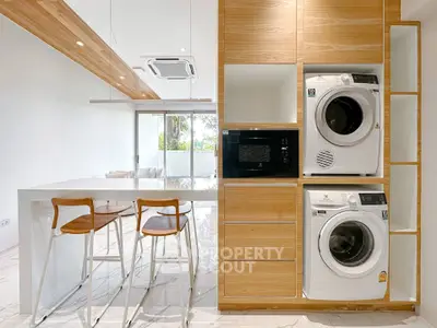 Modern kitchen with wooden cabinetry, built-in appliances, and sleek breakfast bar seating.