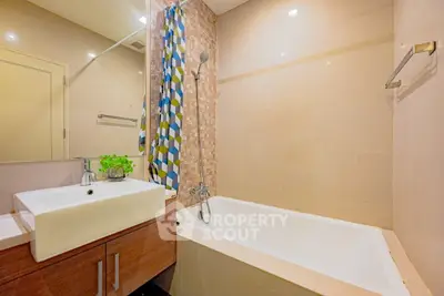 Modern bathroom with stylish sink and bathtub, featuring a colorful shower curtain and elegant tile design.