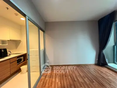 Modern apartment with sleek kitchen and spacious living area featuring wooden flooring.