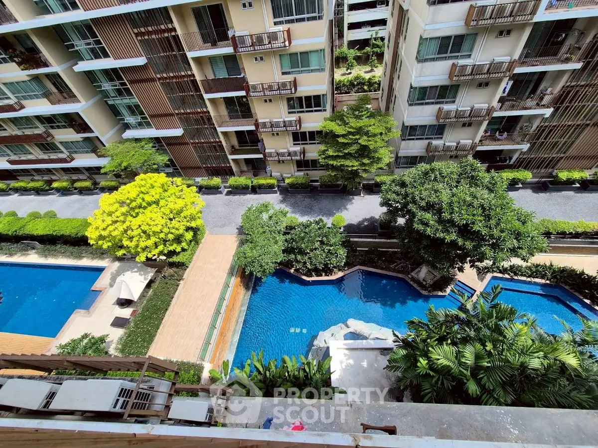 Stunning aerial view of modern apartment complex with lush greenery and inviting swimming pool.