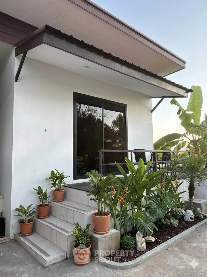 Charming small house exterior with lush garden and potted plants, perfect for cozy living.
