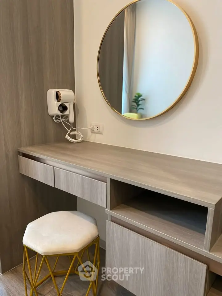 Modern bedroom vanity with round mirror and stylish stool in elegant interior design.