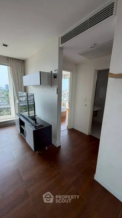 Modern apartment interior with wooden flooring and city view from balcony.