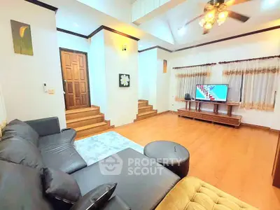 Spacious living room with modern decor and wooden flooring, featuring a cozy sectional sofa and entertainment center.