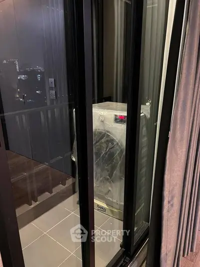 Modern apartment balcony with washing machine and city view at night.