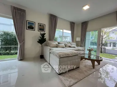 Spacious living room with modern decor and large windows overlooking a lush garden.