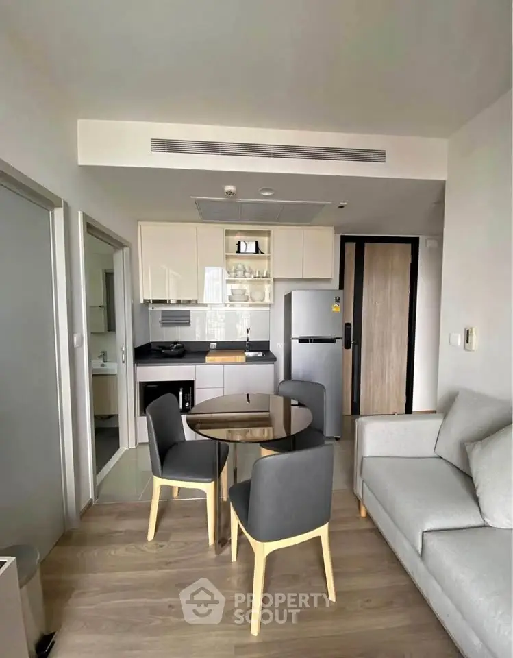Modern apartment interior with open kitchen and cozy living area, featuring sleek furniture and contemporary design.