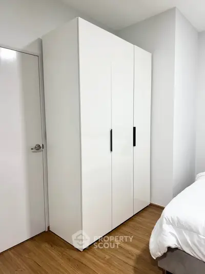 Modern bedroom with sleek white wardrobe and wooden flooring
