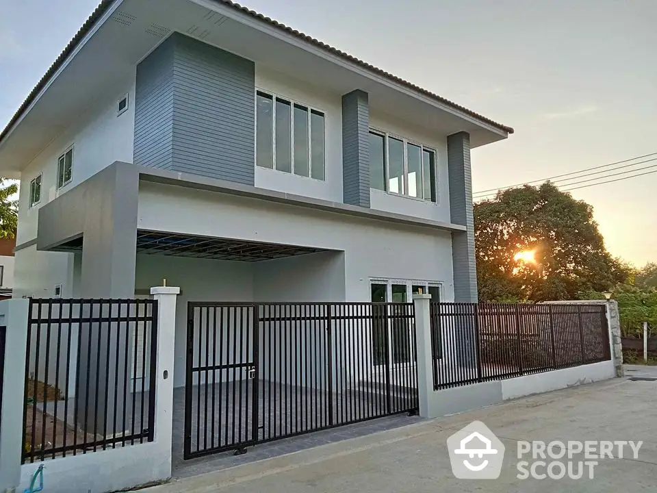 Modern two-story house with sleek design and spacious driveway at sunset.