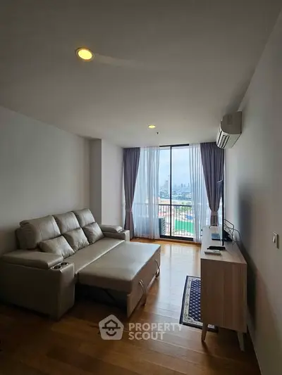 Modern living room with city view, featuring sleek furniture and large windows for natural light.