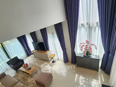 Spacious living room with high ceilings and elegant decor, featuring large windows and modern furniture.
