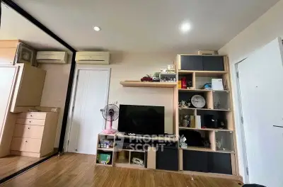 Modern living room with stylish shelving and TV setup, featuring wood flooring and mirrored closet doors.