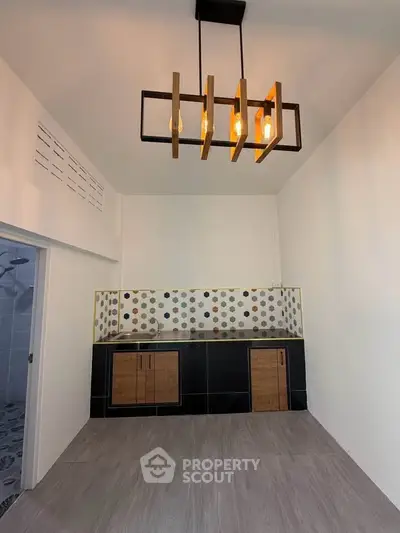 Modern kitchen with stylish lighting and patterned backsplash in a sleek apartment.