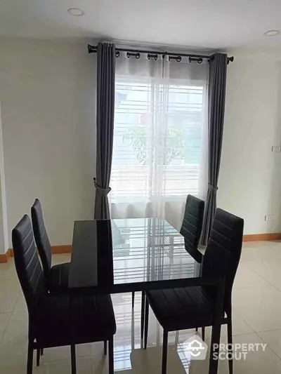 Modern dining area with glass table and black chairs in bright room