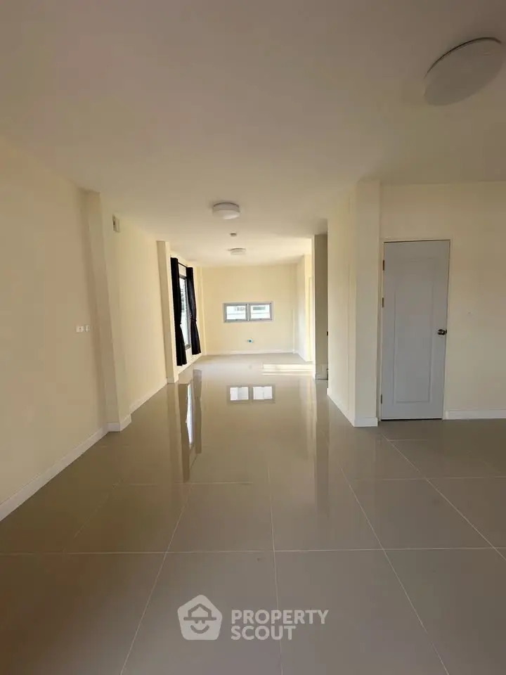 Spacious empty room with glossy tiled floors and neutral walls, perfect for customization.