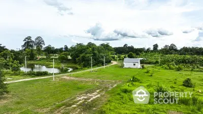 Scenic rural property with lush greenery and a small white house near a pond, ideal for nature lovers.