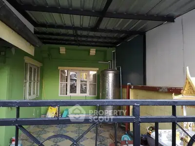 Spacious covered balcony with tiled flooring and green walls, ideal for outdoor relaxation.