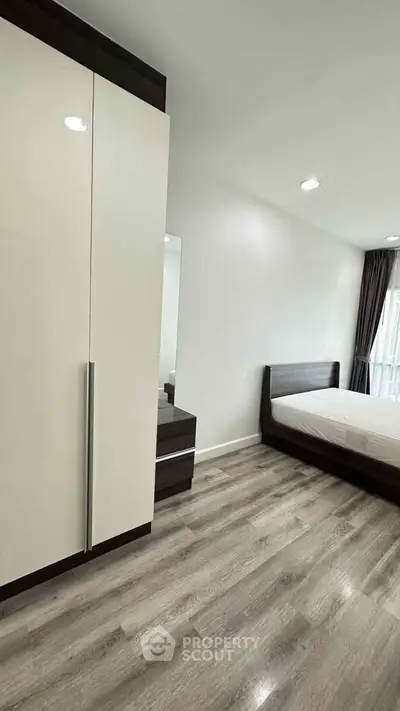 Modern bedroom with sleek wooden flooring and minimalist furniture design.