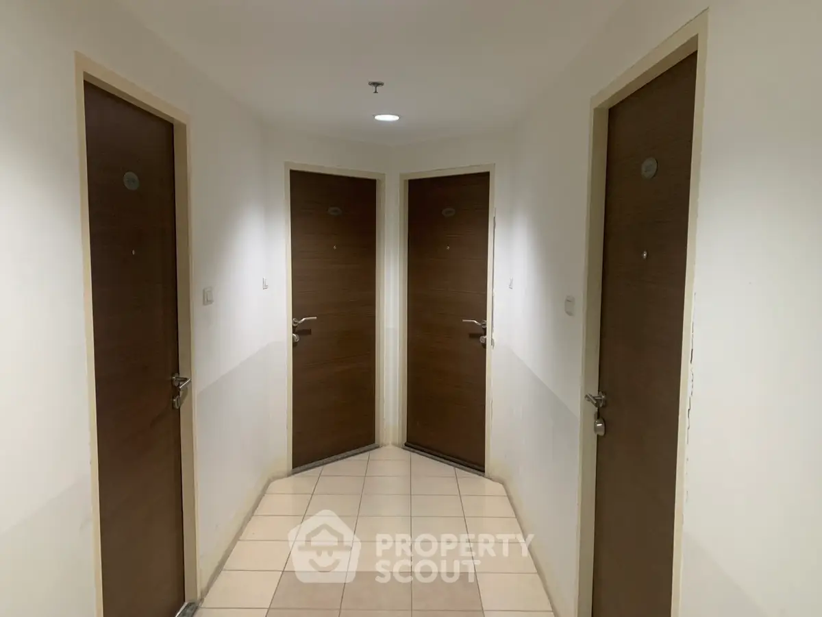 Apartment hallway with four wooden doors and tiled flooring