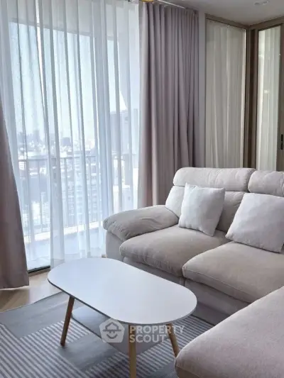 Modern living room with cozy sofa and city view through large windows.