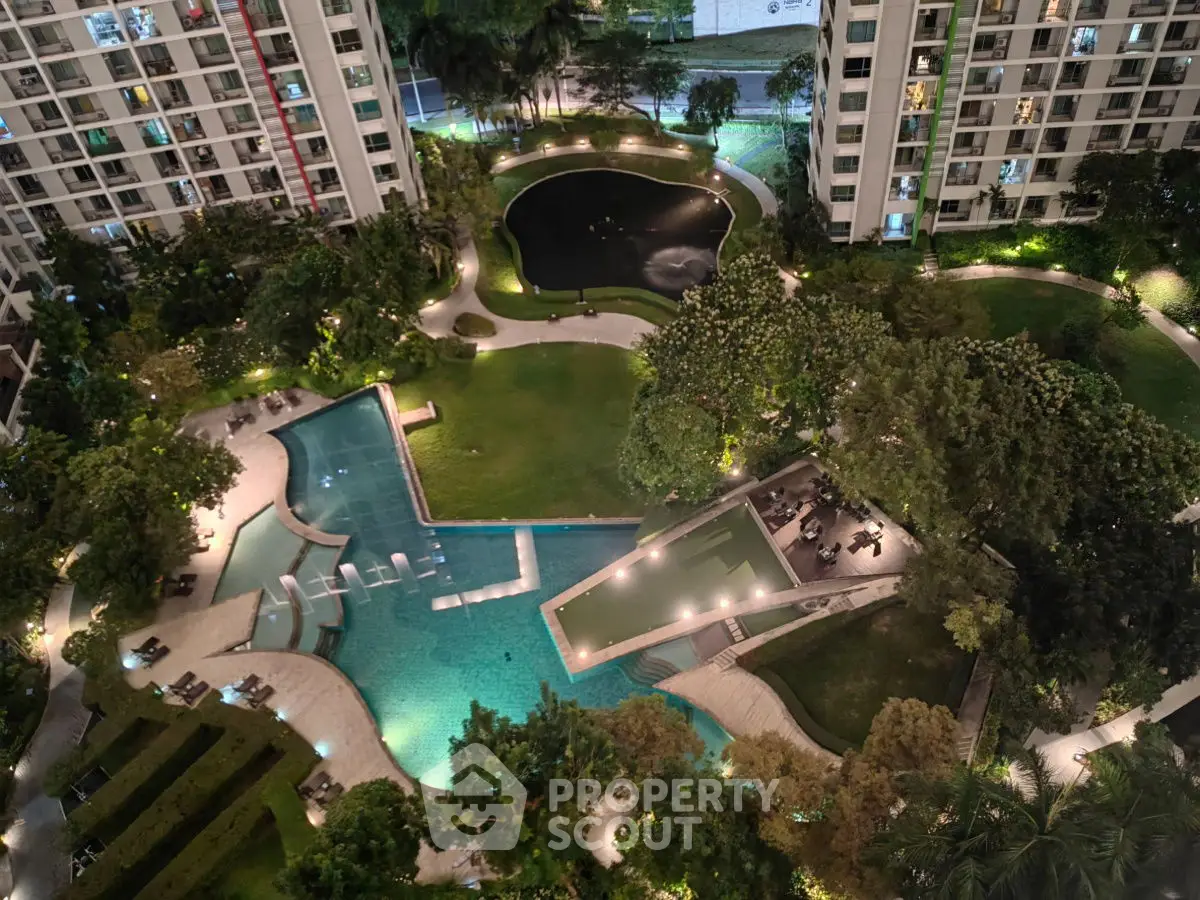 Luxurious residential complex with illuminated pool and lush gardens at night.