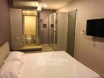 Modern bedroom with ensuite bathroom and wall-mounted TV in a cozy apartment.