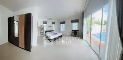 Spacious bedroom with pool view and modern furnishings in luxury home