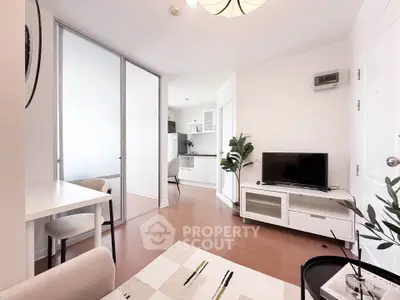 Modern living room with open kitchen, sleek furniture, and bright natural lighting.