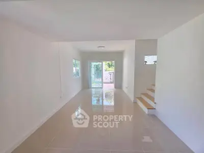 Spacious open-plan living room with glossy tiled floors and natural light.