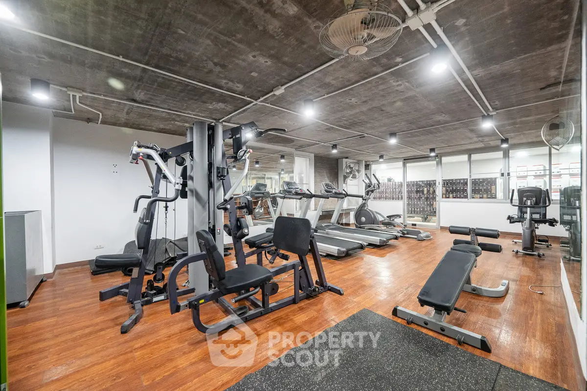 Spacious modern gym with state-of-the-art fitness equipment and wooden flooring.