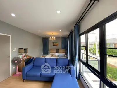 Spacious bedroom with blue sofa and large windows offering natural light