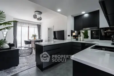 Modern open-layout kitchen and living room with sleek black cabinetry and bright natural light.