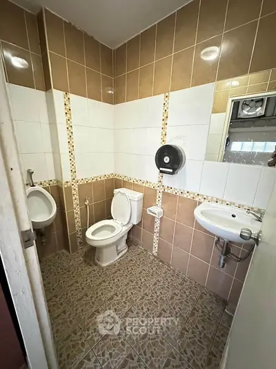Spacious tiled bathroom with modern fixtures and ample lighting.