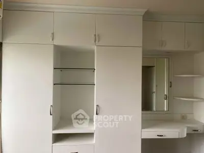 Spacious white built-in wardrobe with mirror and shelves in modern bedroom.