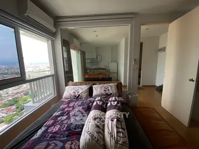 Modern bedroom with city view and open kitchen layout in high-rise apartment