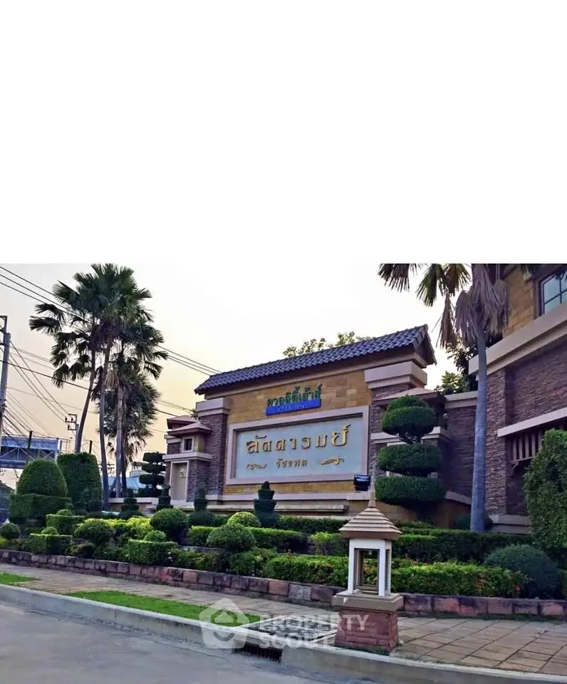 Elegant entrance of a residential community with lush landscaping and signage.