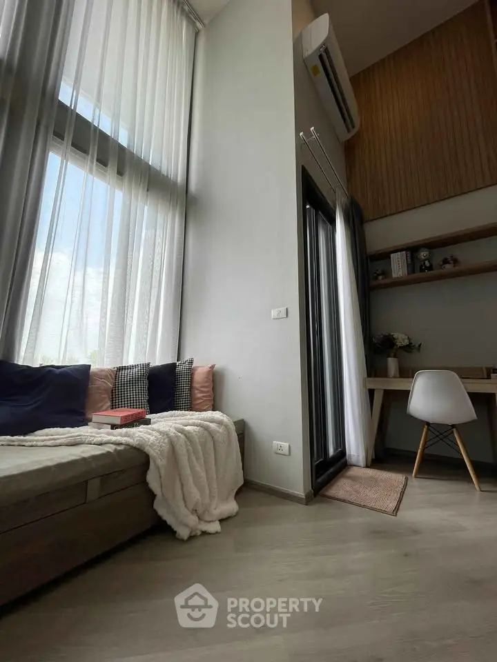 Modern living room with high ceilings, large windows, and cozy seating area.