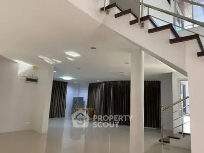 Spacious modern living room with sleek staircase and large windows