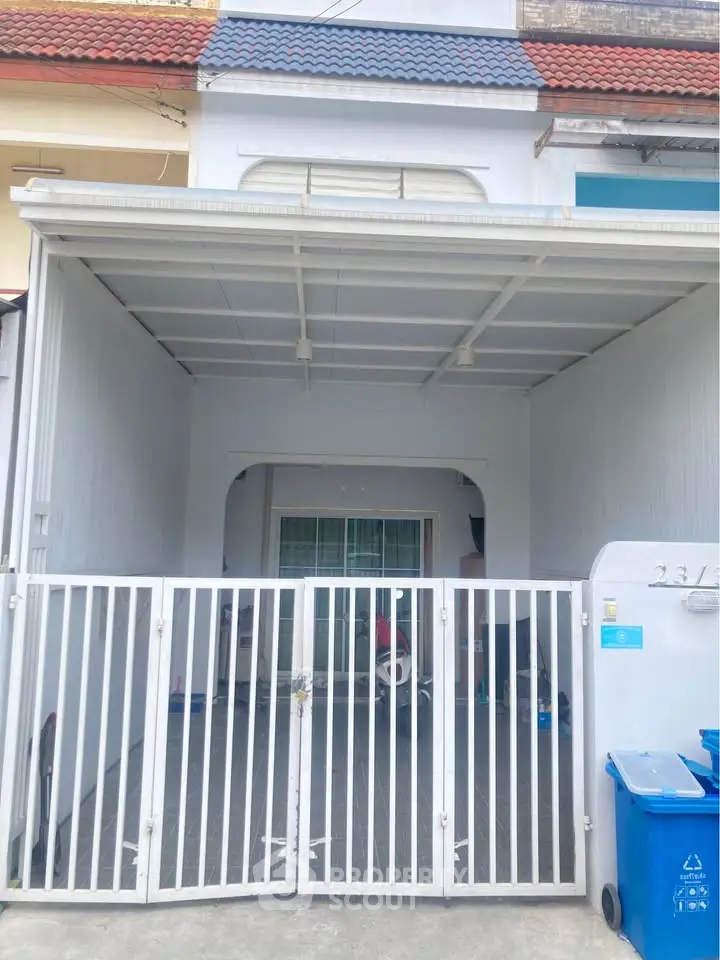 Charming townhouse exterior with gated entrance and covered parking area.