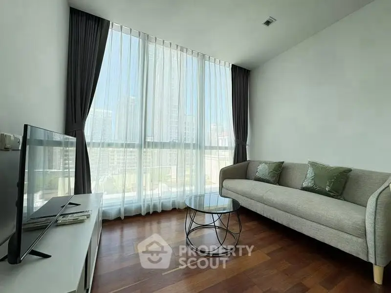 Modern living room with large windows and stylish furniture in a high-rise apartment.