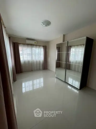 Spacious bedroom with large mirrored wardrobe and natural light