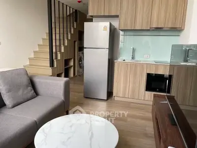 Modern open-plan living room with kitchen, featuring sleek appliances and stylish decor.