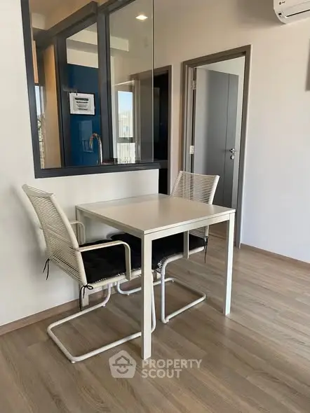 Modern dining area with sleek table and chairs, featuring a window to the kitchen.